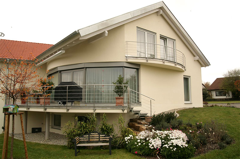 Einfamilienhaus in offener Winkelbauweise mit schöner Panorama-Aussicht durch die abgerundete Fensterfront.